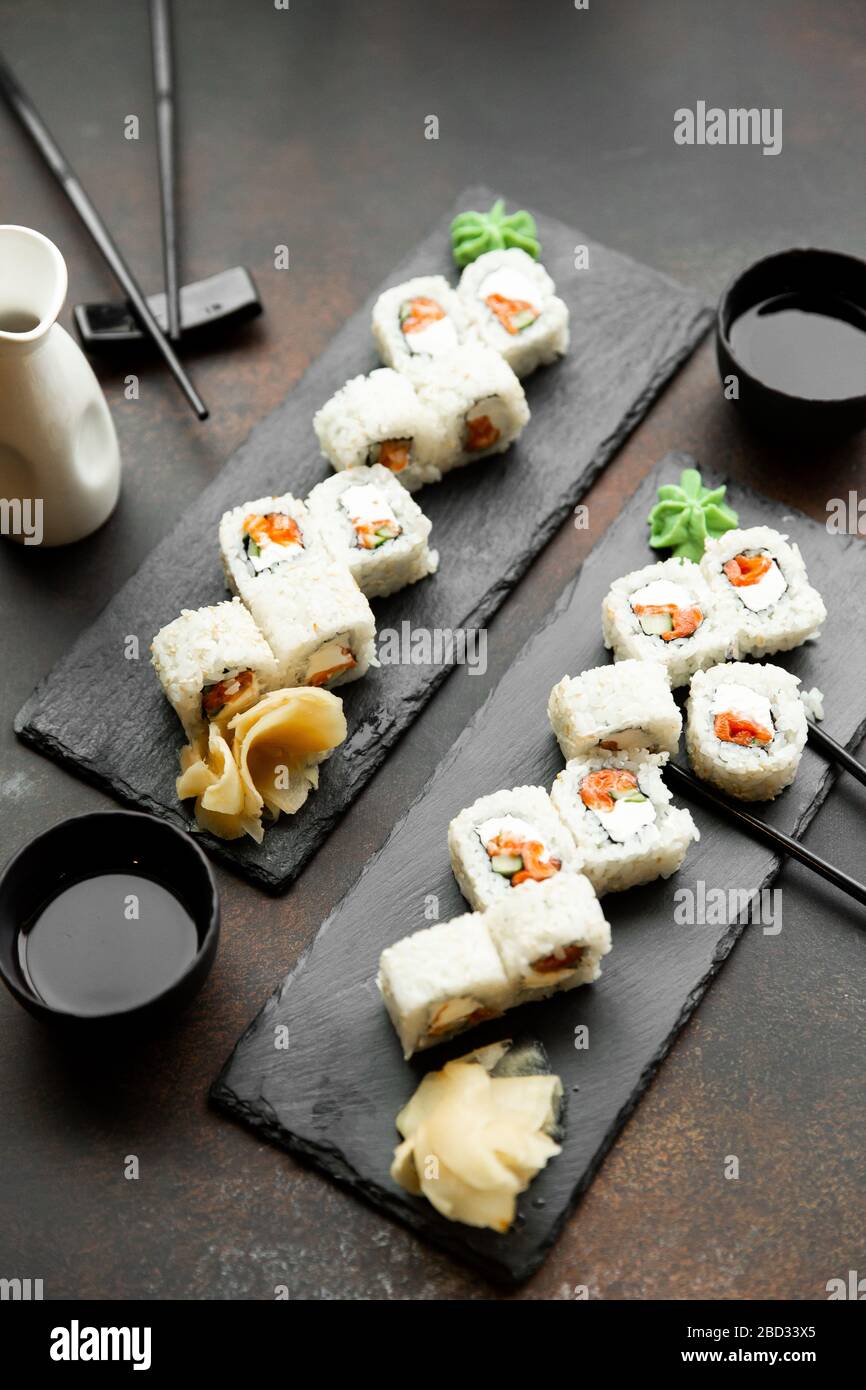 sushi pour deux. Kit pour deux avec baguettes, gingembre, soja, wasabi. Vue sur le fond en bois et les plaques d'ardoise noires. Banque D'Images