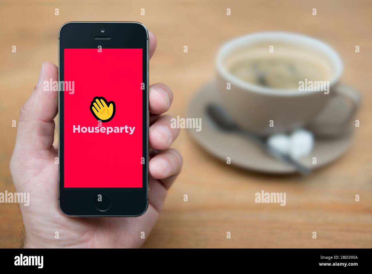 Un homme regarde son iPhone qui affiche le logo Houseparty (usage éditorial uniquement). Banque D'Images Un homme regarde son iPhone qui affiche le logo Houseparty (usage éditorial uniquement). Banque D'Images