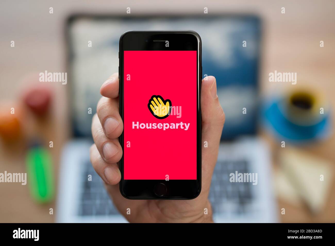 Un homme regarde son iPhone qui affiche le logo Houseparty (usage éditorial uniquement). Banque D'Images Un homme regarde son iPhone qui affiche le logo Houseparty (usage éditorial uniquement). Banque D'Images