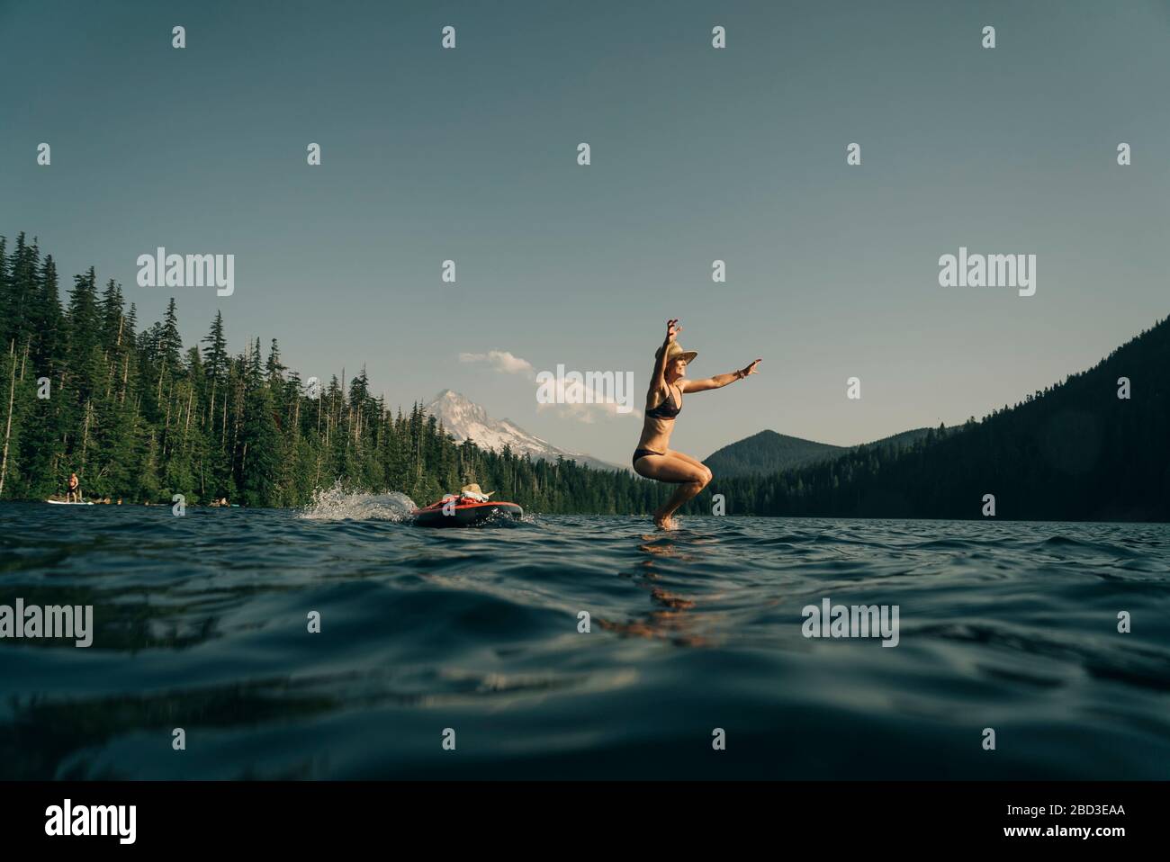 Une jeune femme saute d'un paddle board à Lost Lake en Oregon. Banque D'Images