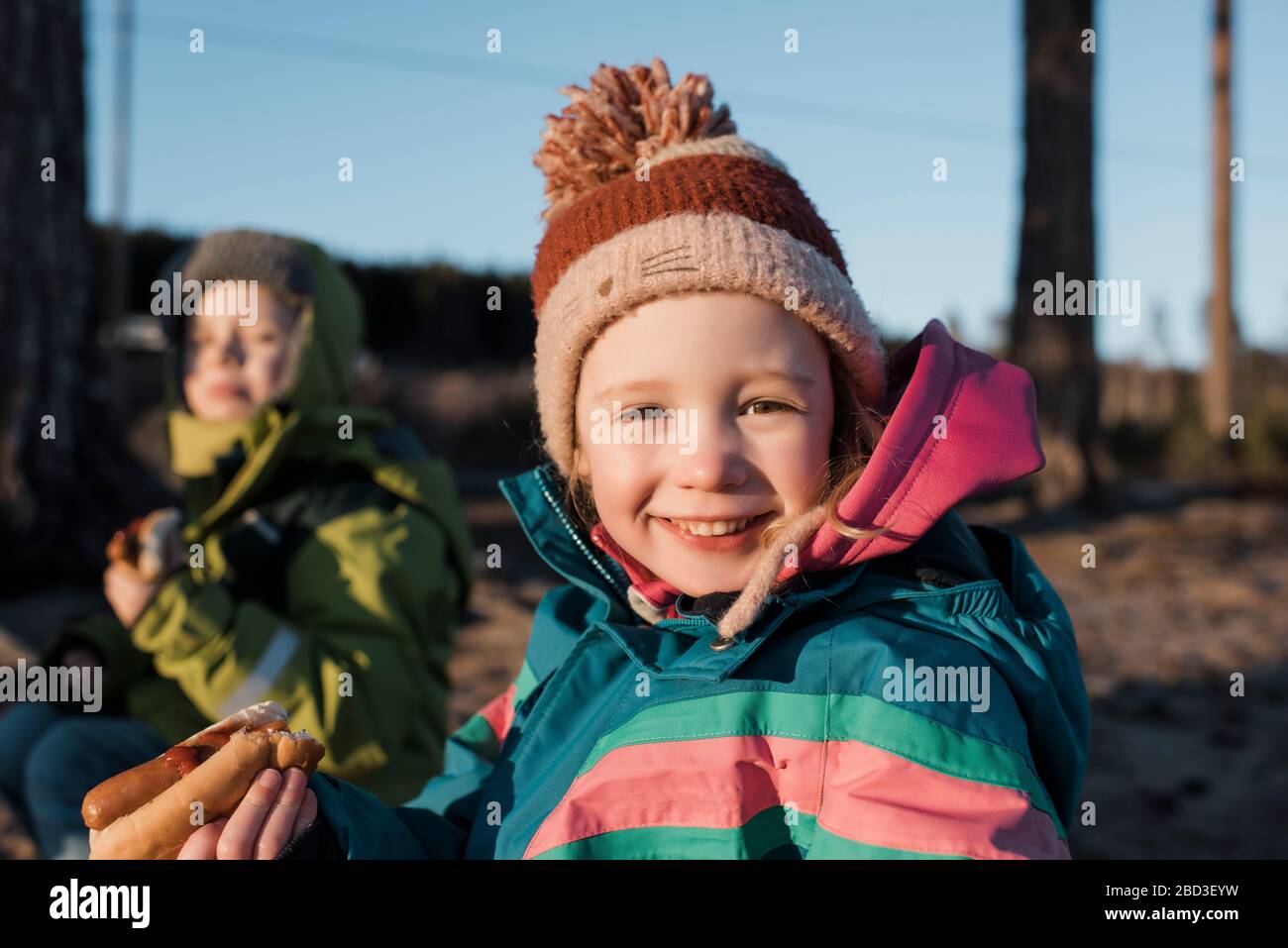 Portrait d'une jeune fille mangeant un hot dog par un feu de camp en Suède Banque D'Images