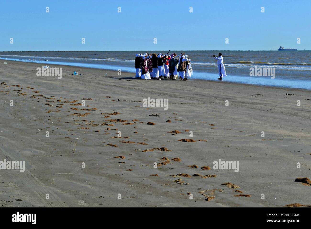 Des femmes noires et un prêtre prient sur la plage de Galveston, Texas Banque D'Images