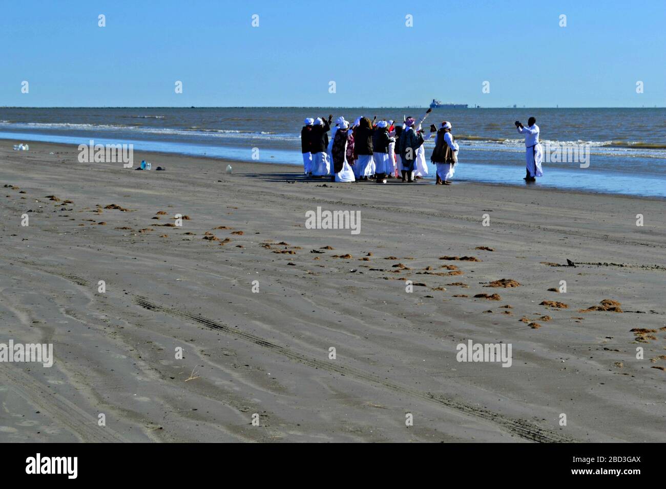Des femmes noires et un prêtre prient sur la plage de Galveston, Texas Banque D'Images