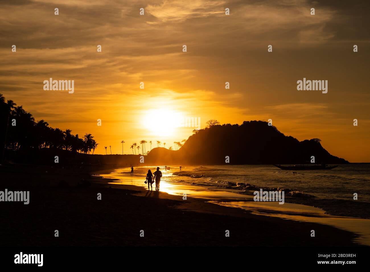 Deux personnes silhouettées marchent au coucher du soleil sur la plage de Nacpan à El Nido, Palawan, Philippines Banque D'Images