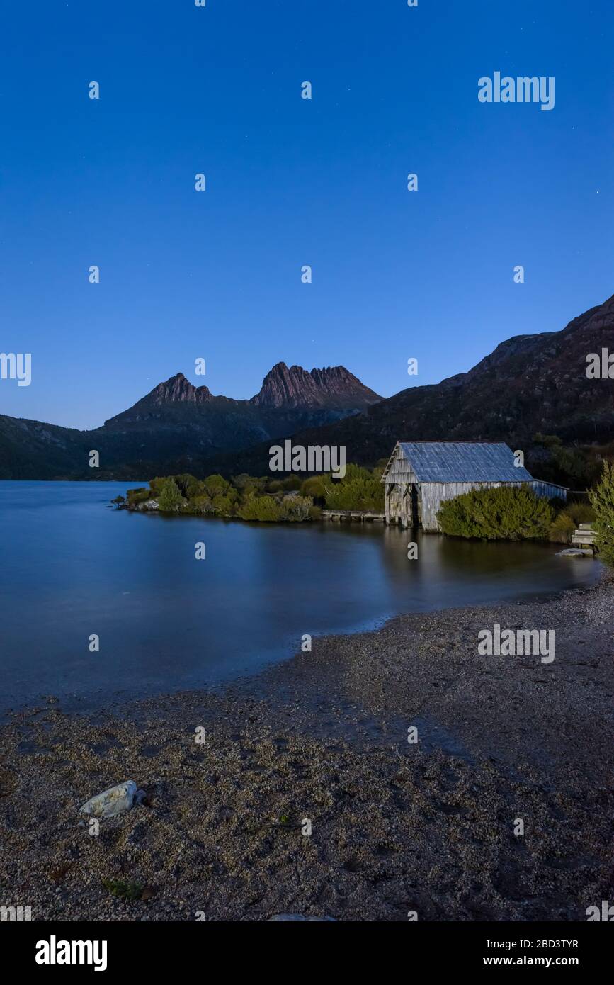 Des étoiles de l'heure bleue qui commencent à couvrir le légendaire lac Dove et le hangar de boatshed, menant aux deux pics de Cradle Mountain sur un ciel de nuit clair en Tasmanie. Banque D'Images