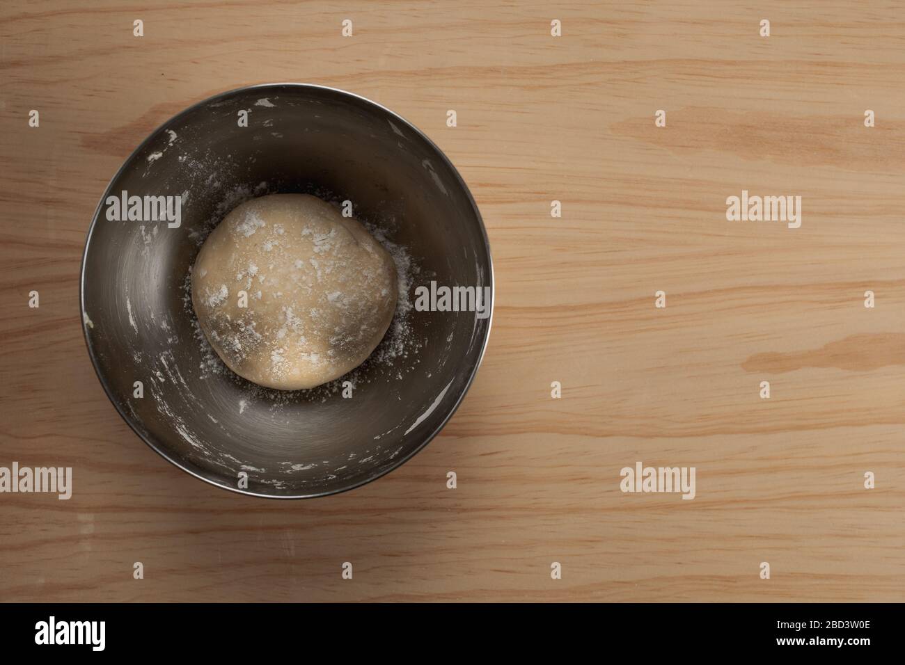Vue en hauteur d'une boule de pâte à pizza avec farine dans un bol en fer sur une table en bois Banque D'Images