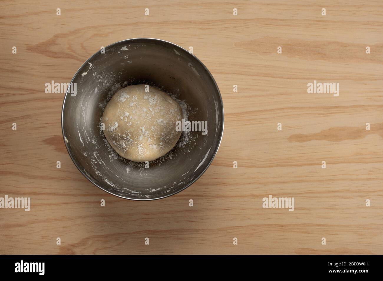 Vue en hauteur d'une boule de pâte à pizza avec farine dans un bol en fer sur une table en bois Banque D'Images