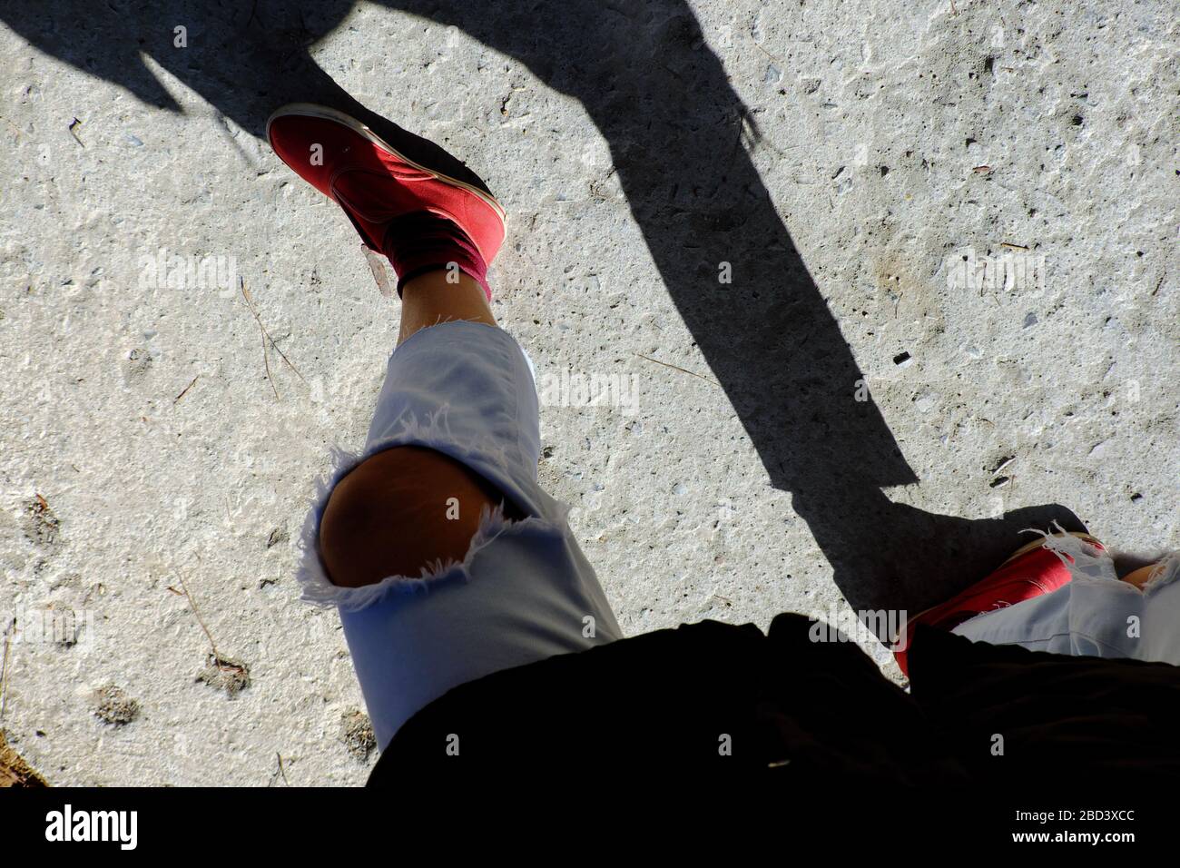 Une vue imprenable lorsque la photographe féminine s'est égoïste tôt le matin, une ombre drôle de jean déchiré au genou et des chaussures rouges des gens debout Banque D'Images