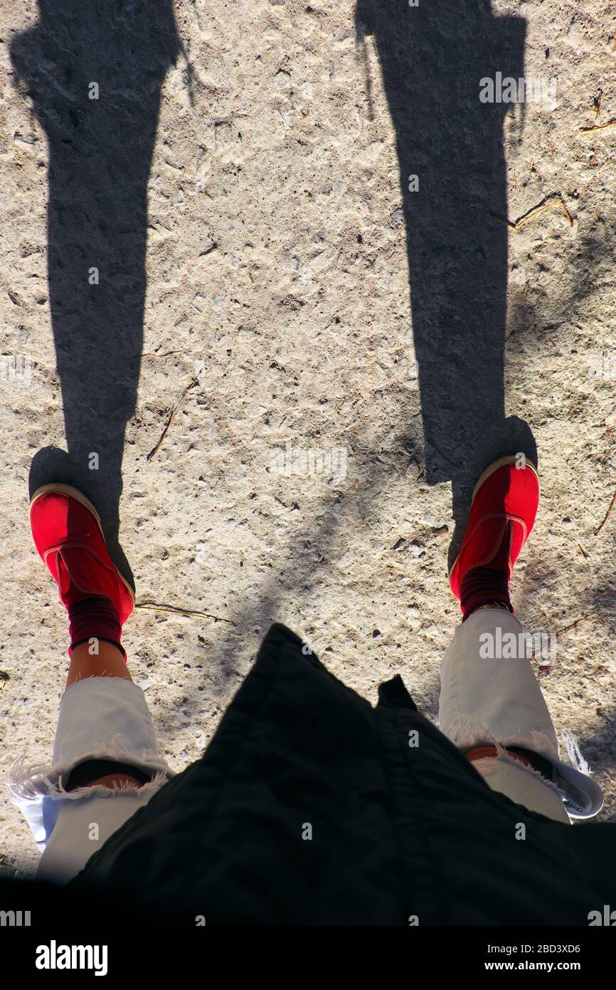 Une vue imprenable lorsque la photographe féminine s'est égoïste tôt le matin, une ombre drôle de jean déchiré au genou et des chaussures rouges des gens debout Banque D'Images
