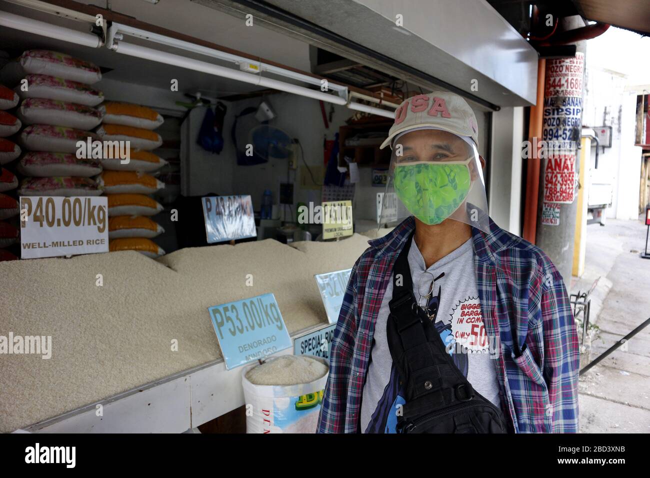 Antipolo City, Philippines - 4 avril 2020: Homme avec équipement de protection personnelle improvisé et masque de visage acheter du riz dans un magasin pendant le verrouillage Banque D'Images