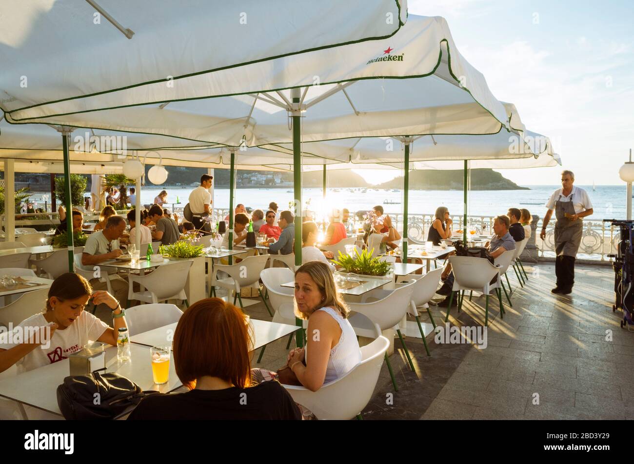 San Sebastian, Gipuzkoa, pays Basque, Espagne : les gens se détendent au coucher du soleil dans un café-terrasse chic sur la promenade de la plage de la Concha. Banque D'Images