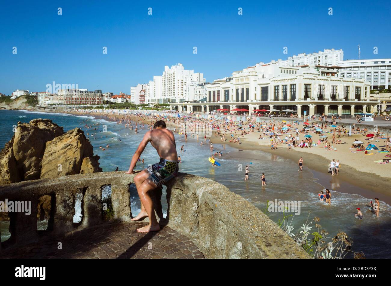 Biarritz, Pays basque français, France - 19 juillet 2019 : un jeune homme regarde la Grande Plage, la plus grande plage de la ville. Casino de style art déco Banque D'Images