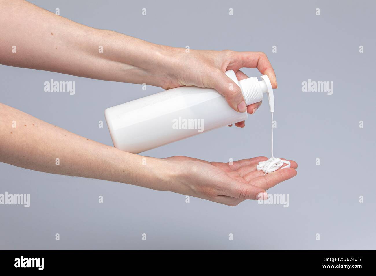 Les mains des blancs se lavant les unes les autres avec le savon de Marseille vert mousse isolé devant un fond gris avec des lumières et des ombres structurantes Banque D'Images