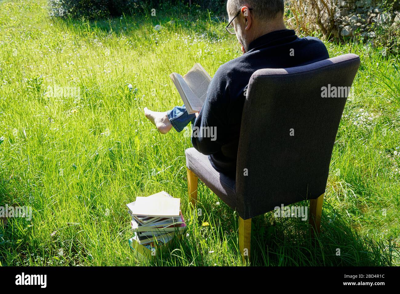un homme lit un livre dans la pelouse du jardin pendant une quarantaine de coronavirus Banque D'Images