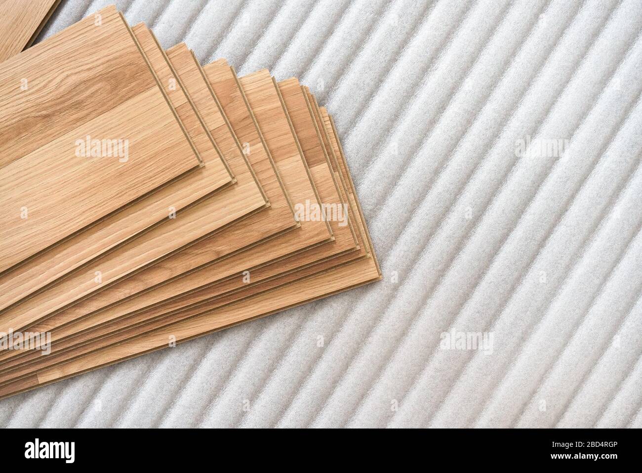 Installation d'un plancher laminé, détail sur des tuiles en bois disposées sur une couche de base en mousse blanche Banque D'Images