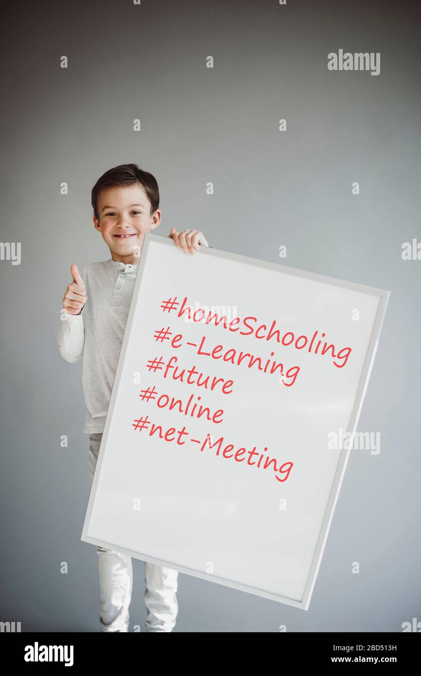 garçon tenant le signe blanc avec les mots homeschooling et plus devant le fond gris pendant la crise de la couronne Banque D'Images