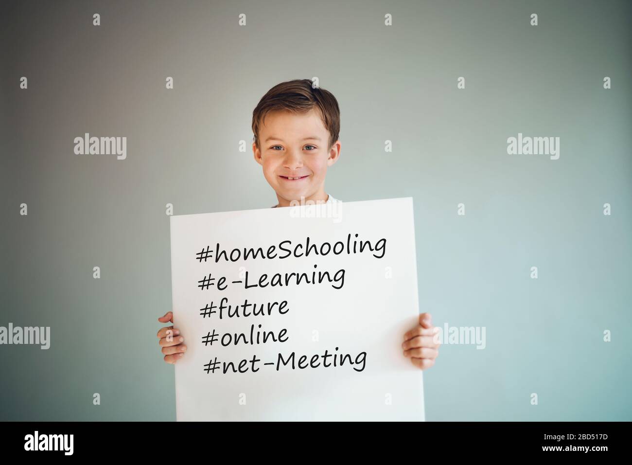 garçon tenant le signe blanc avec les mots homeschooling et plus devant le fond gris pendant la crise de la couronne Banque D'Images