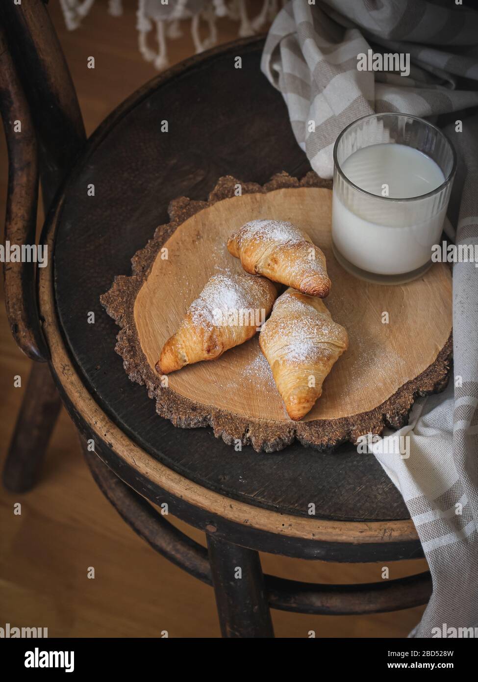 Croissants et lait servis sur une vieille chaise. Humeur sombre Banque D'Images