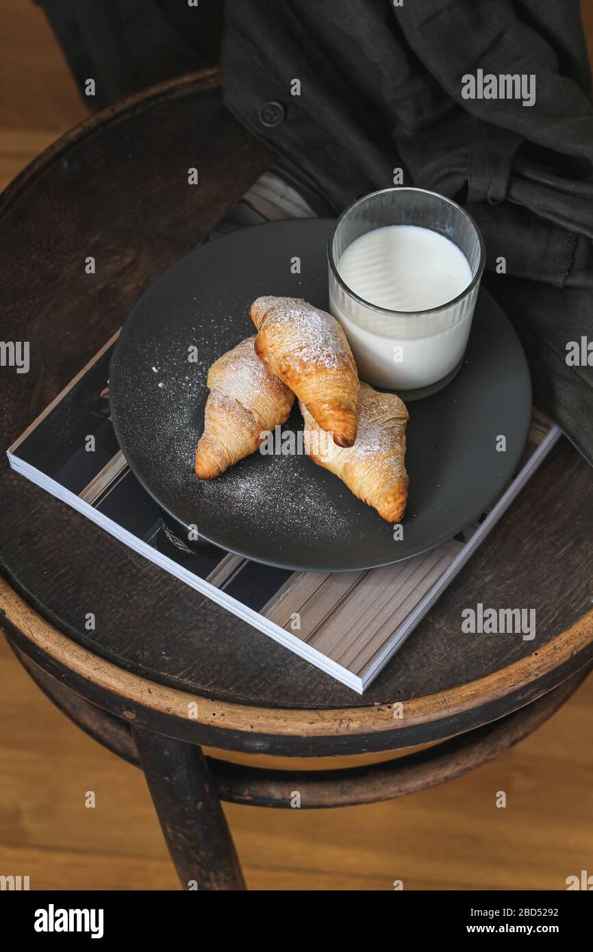 Croissants maison et un verre de lait servis sur une chaise ancienne Banque D'Images