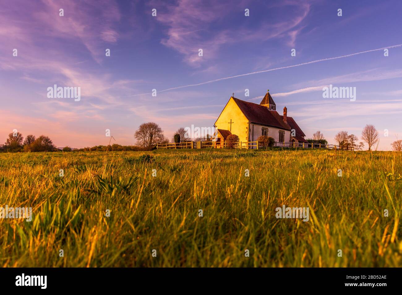 L'église isolée Saint-Hubert, entourée de champs dans le parc national de South Downs, tandis que le soleil commence à se coucher pendant l'heure d'or Banque D'Images