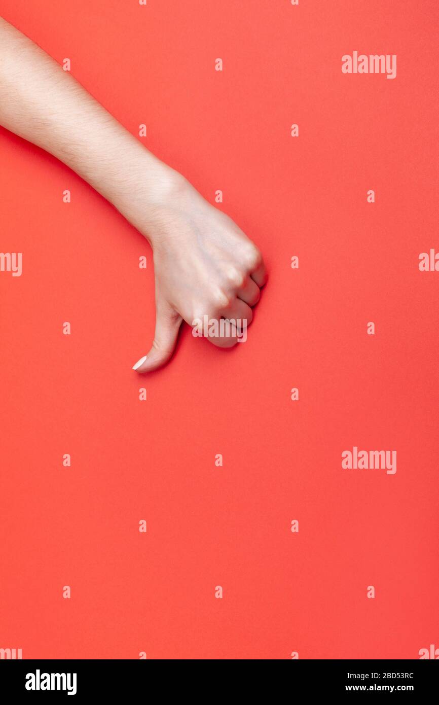 La main féminine montre le pouce vers le bas sur fond rouge, placez pour le texte Banque D'Images