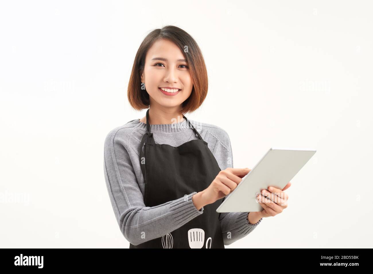 Heureux propriétaire de petite entreprise dans le tablier tenant la tablette debout sur fond blanc Banque D'Images