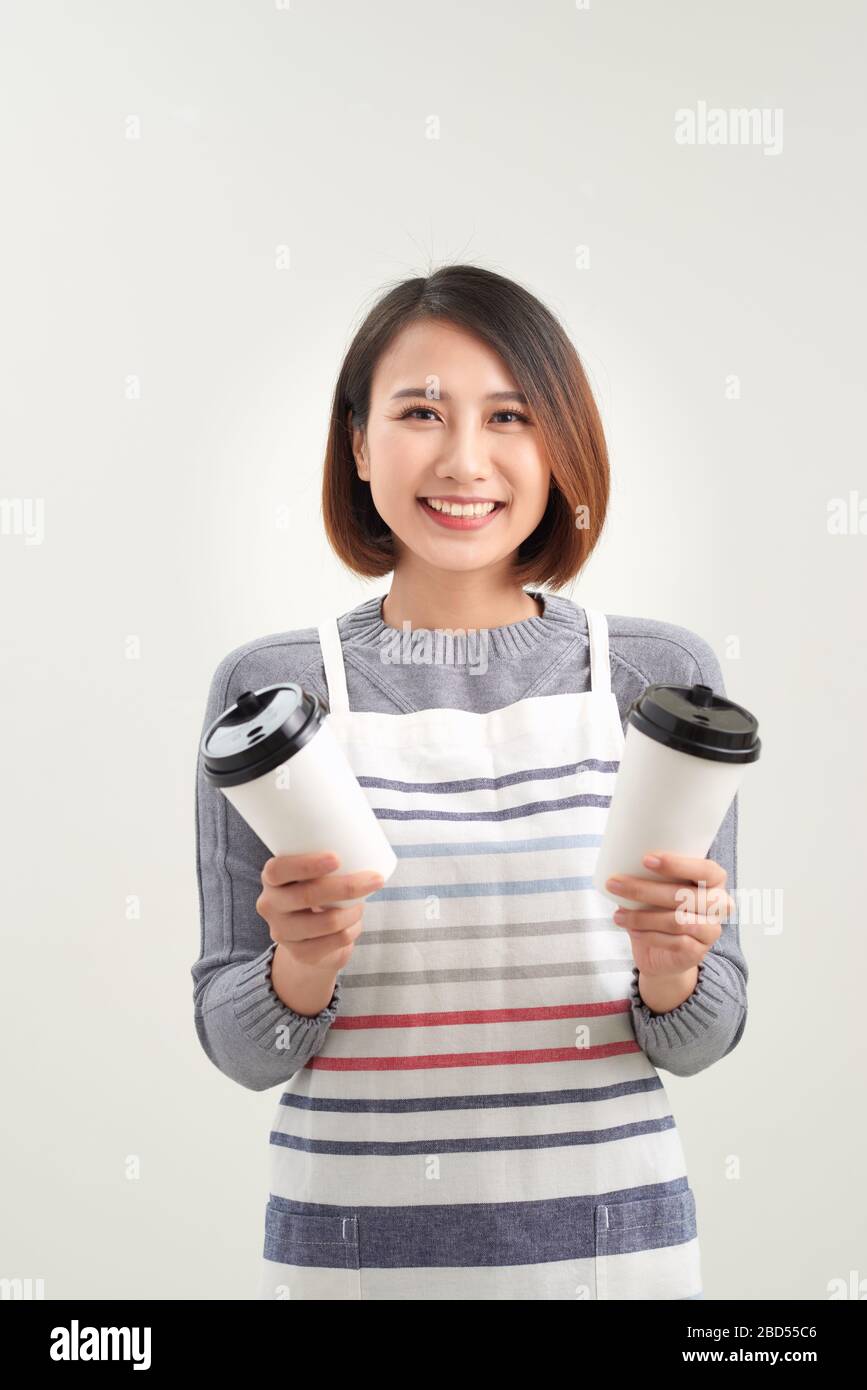 Gros plan photo magnifique sa femme serveuse propriétaire cafétéria tenir les mains bras en papier tasses boisson chaude inviter visite café porter tablier isolé W Banque D'Images