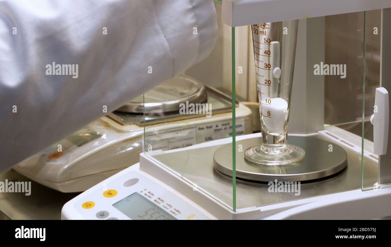 Scientifique avec revêtement de laboratoire remplissant un tube de test sur l'équilibre analytique avec des produits chimiques dans le laboratoire Banque D'Images