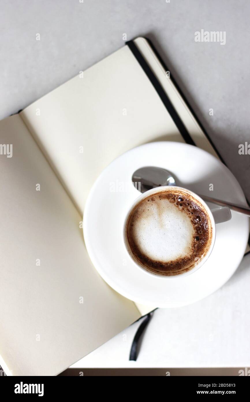 Tasse de café fraîche sur cahier vierge ouvert. Travail à partir de la maison. Banque D'Images
