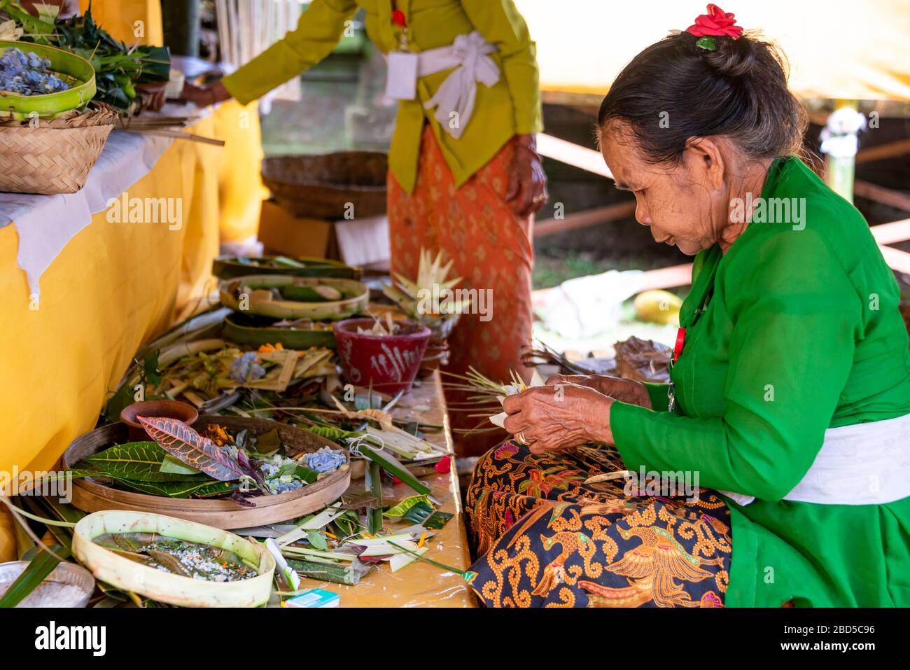 Vue horizontale des femmes faisant des décorations traditionnelles dans un temple à Bali, Indonésie. Banque D'Images