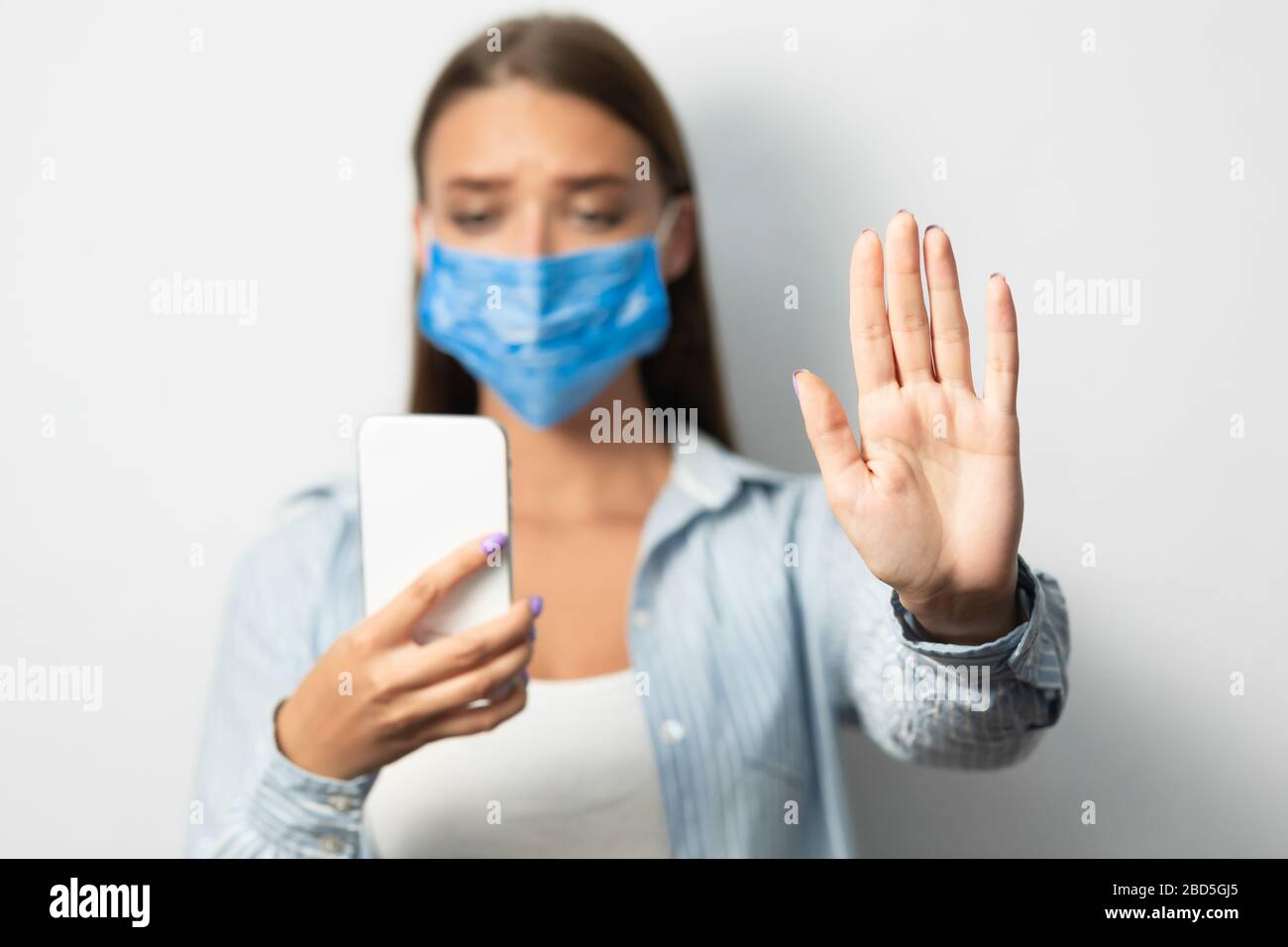 Femme tenant smartphone gestuelle arrêtez-vous debout sur fond blanc Banque D'Images
