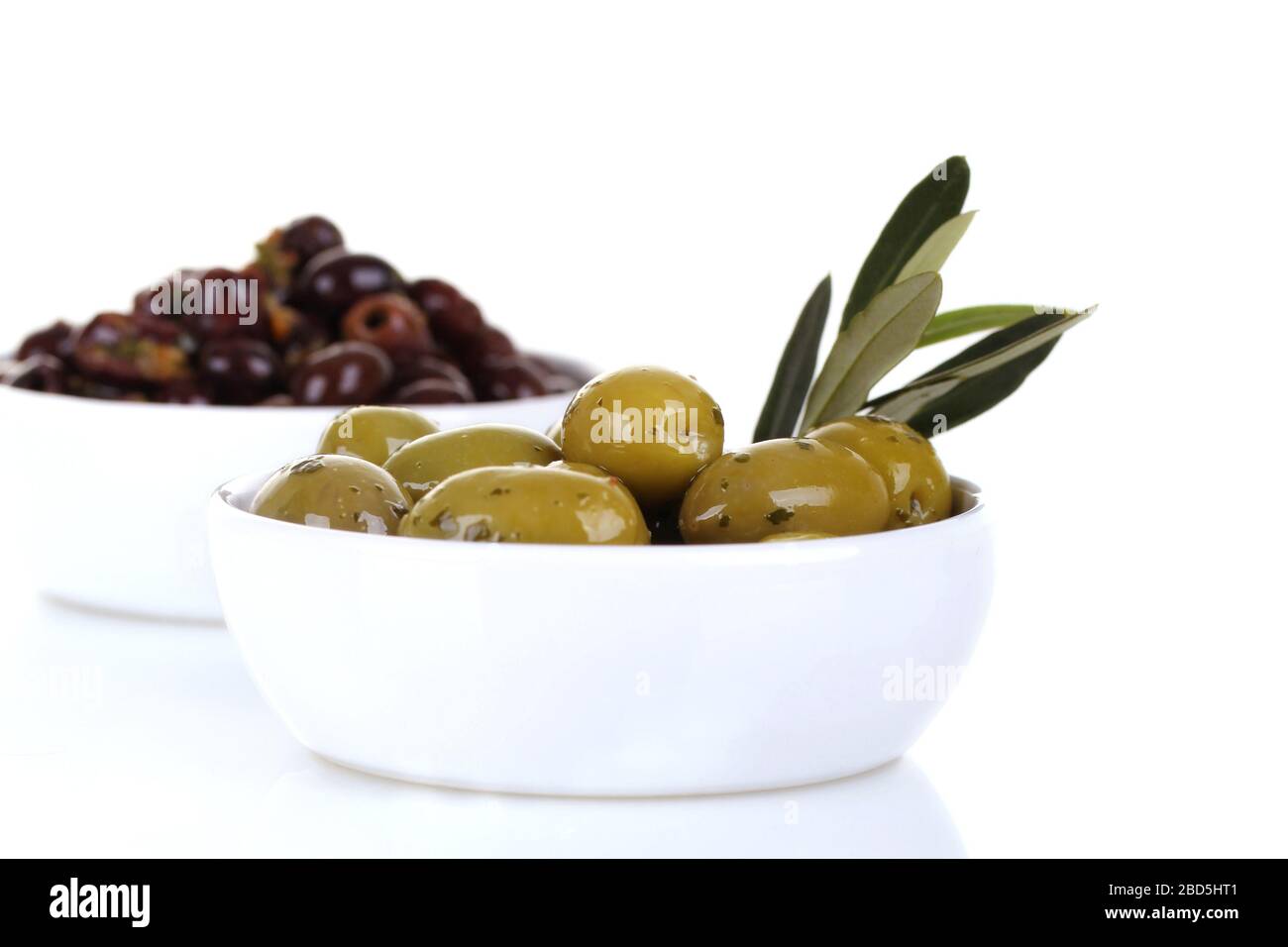 Olives vertes et noires dans des bols blancs sur blanc. Faible profondeur de champ intentionnelle. Banque D'Images