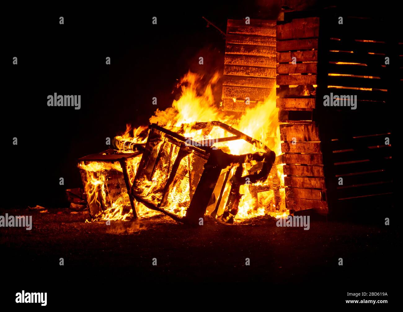 Un feu de caisses en bois incendié dans l'obscurité avec des flammes orange vives et un fond sombre Banque D'Images