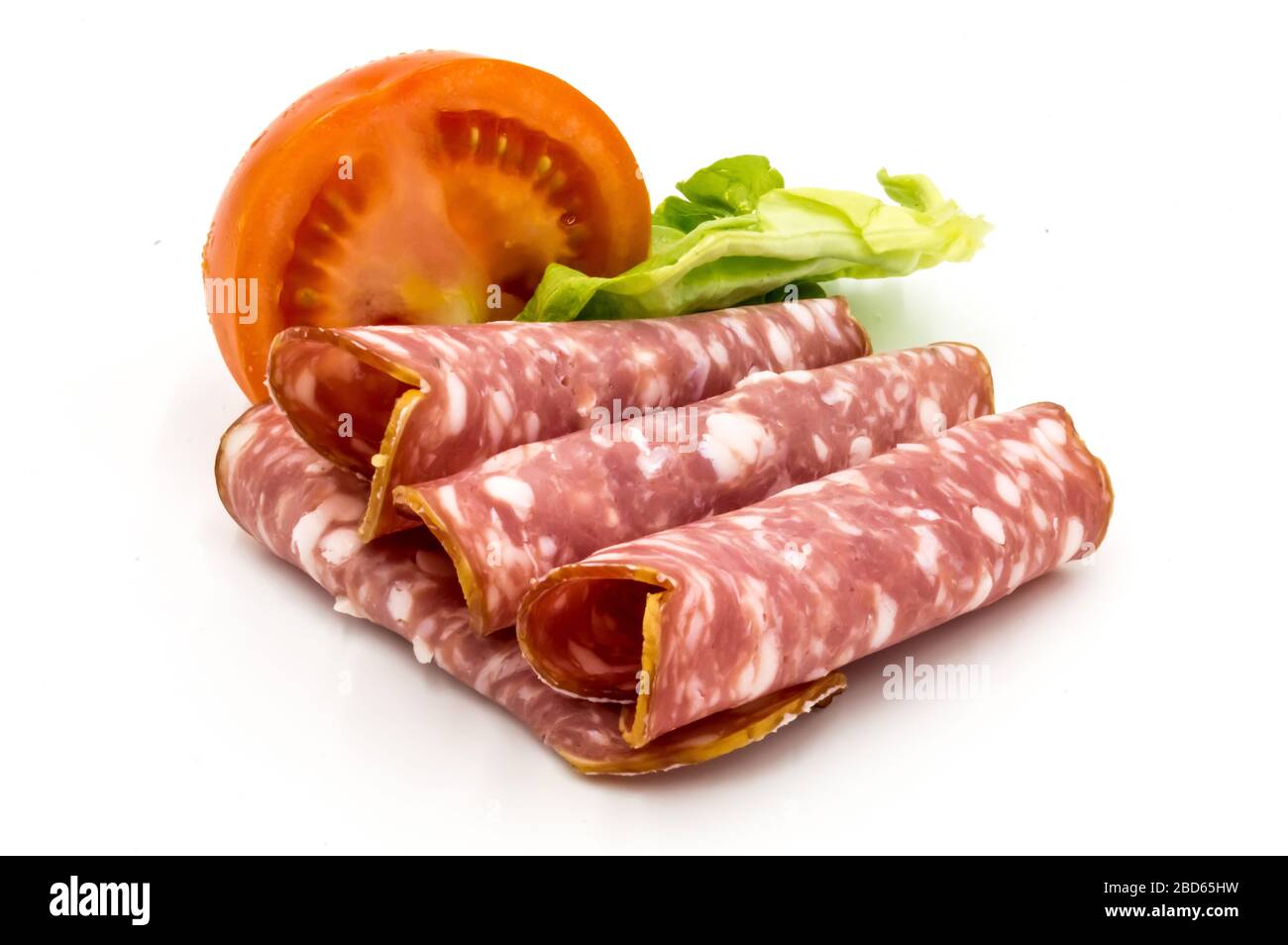 Tranche de saucisse de Gaumais sur fond blanc avec une demi-tomate et une feuille de salade Banque D'Images
