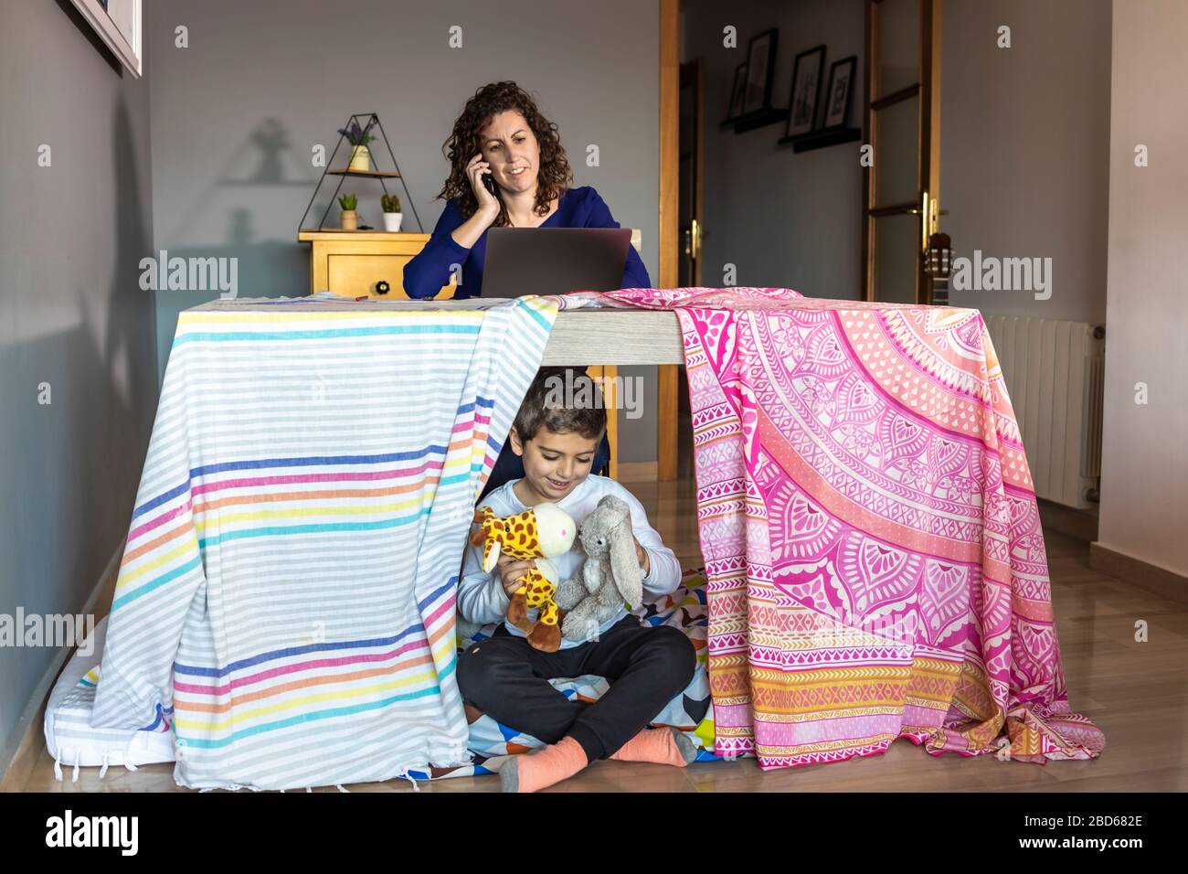 Mère travaillant à la maison pendant que son fils joue Banque D'Images