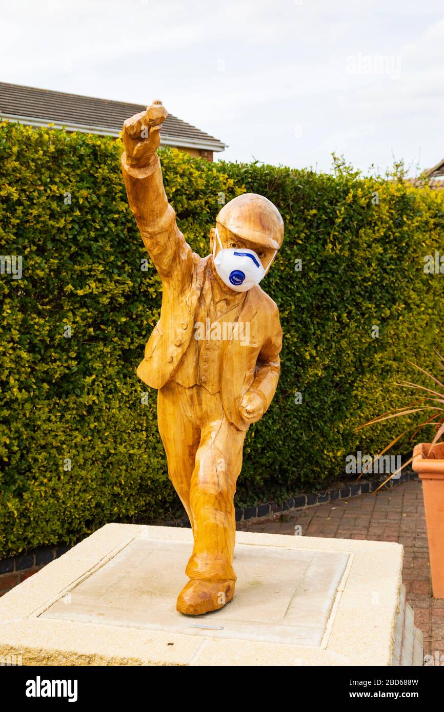 Statue de « Clockpelter » portant un masque médical pendant la pandémie du virus Covid-19 Corona. Great Gonerby, Grantham, Lincolnshire, Angleterre. Avril 2020 Banque D'Images
