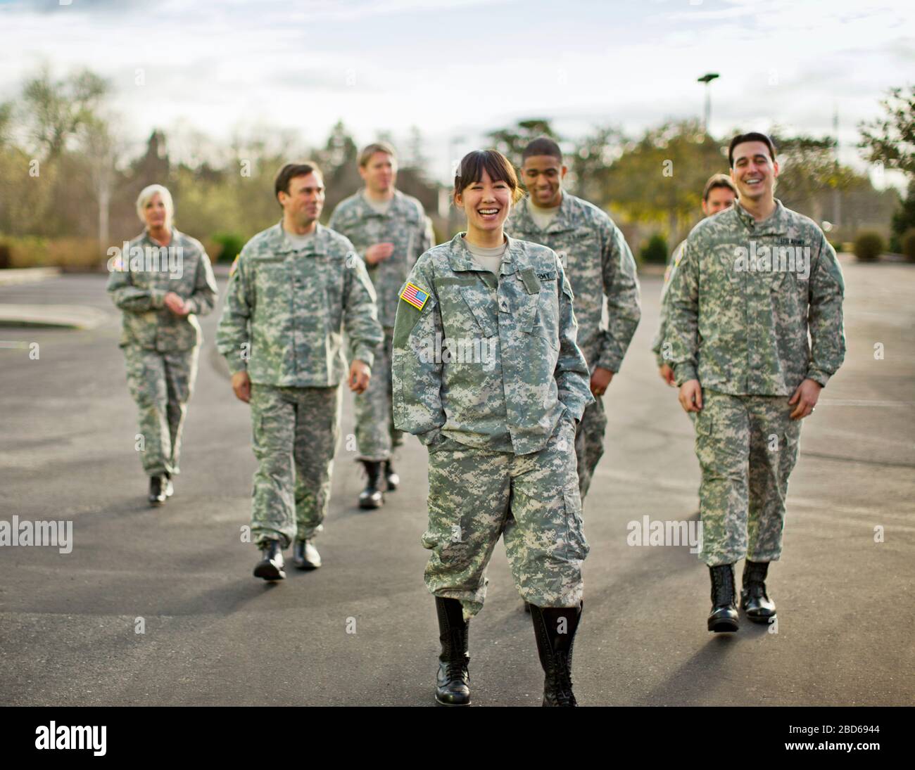 Un groupe de soldats de l'armée américaine sourient et rient ensemble lorsqu'ils traversent un parking après un exercice d'entraînement. Banque D'Images