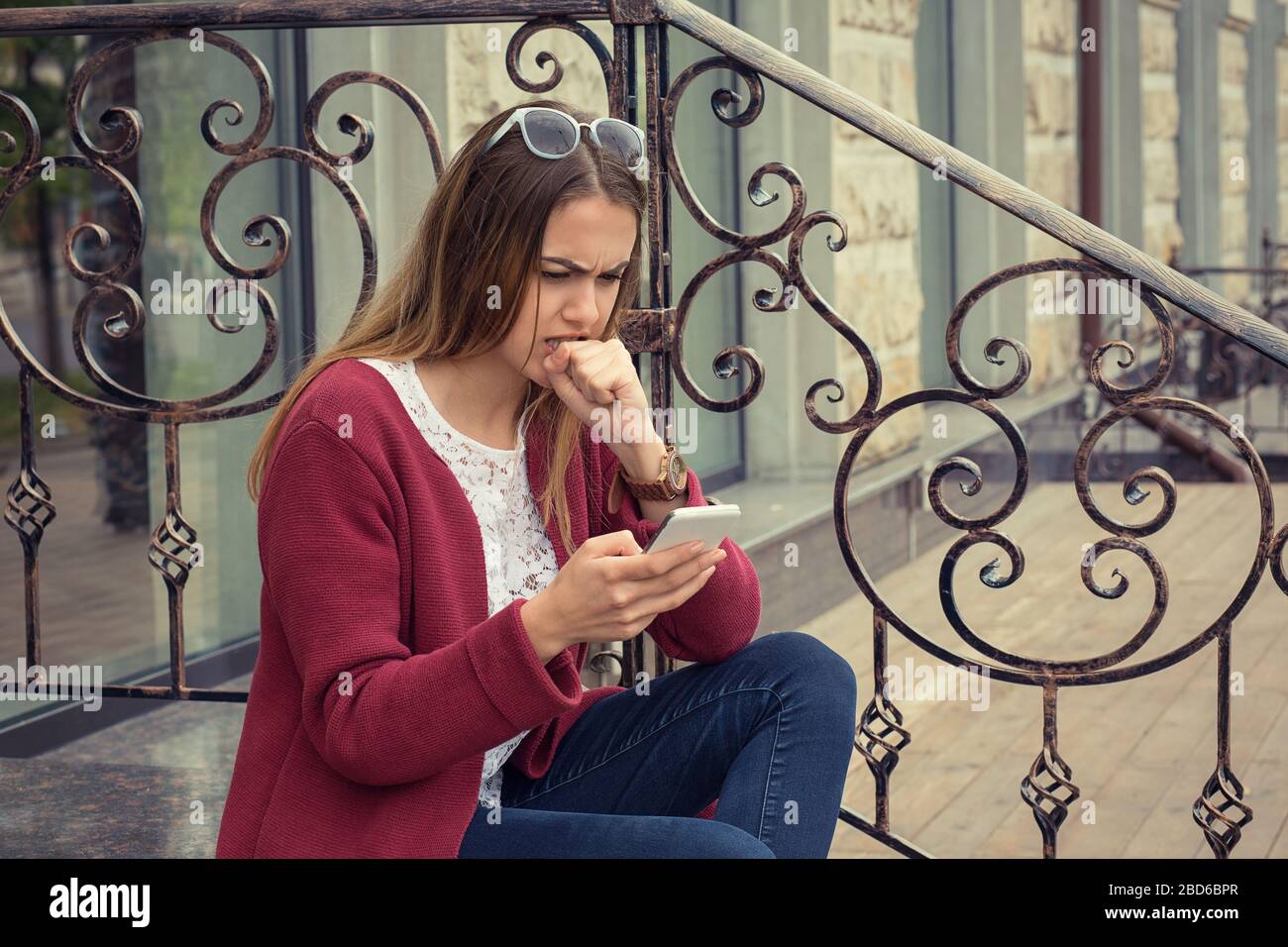 Femme anxieuse regardant les médias dans un téléphone mobile assis dehors près de sa maison dans Manhattan New York fond Banque D'Images