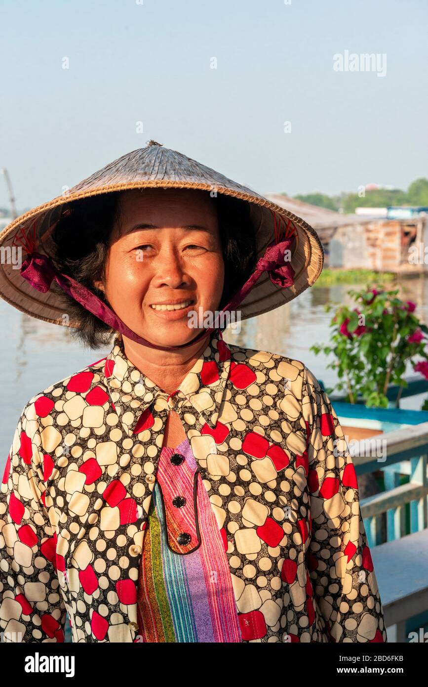 Femme vietnamienne souriante vivant dans une maison flottante et portant un chapeau conique traditionnel sur le delta du Mékong, Vietnam, Asie du Sud-est Banque D'Images