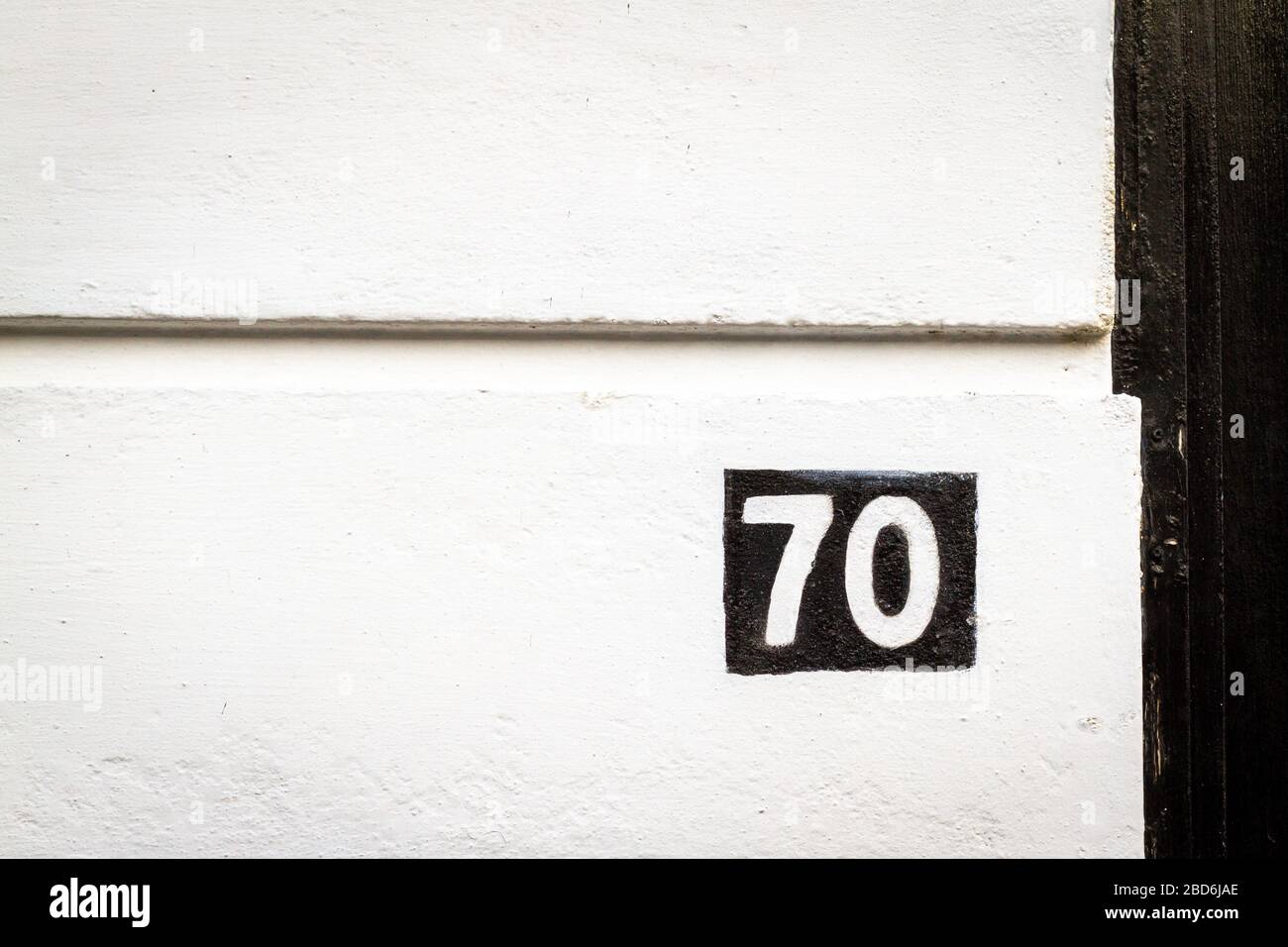 Maison numéro 70 peinte à l'inverse sur un mur de maison Banque D'Images