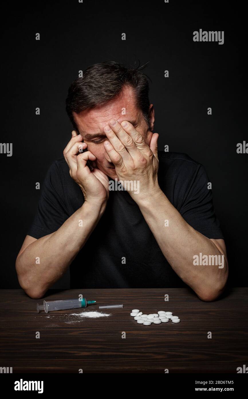 L'homme drogue accro appelle au téléphone pour l'aide, une pose de désespoir. Banque D'Images
