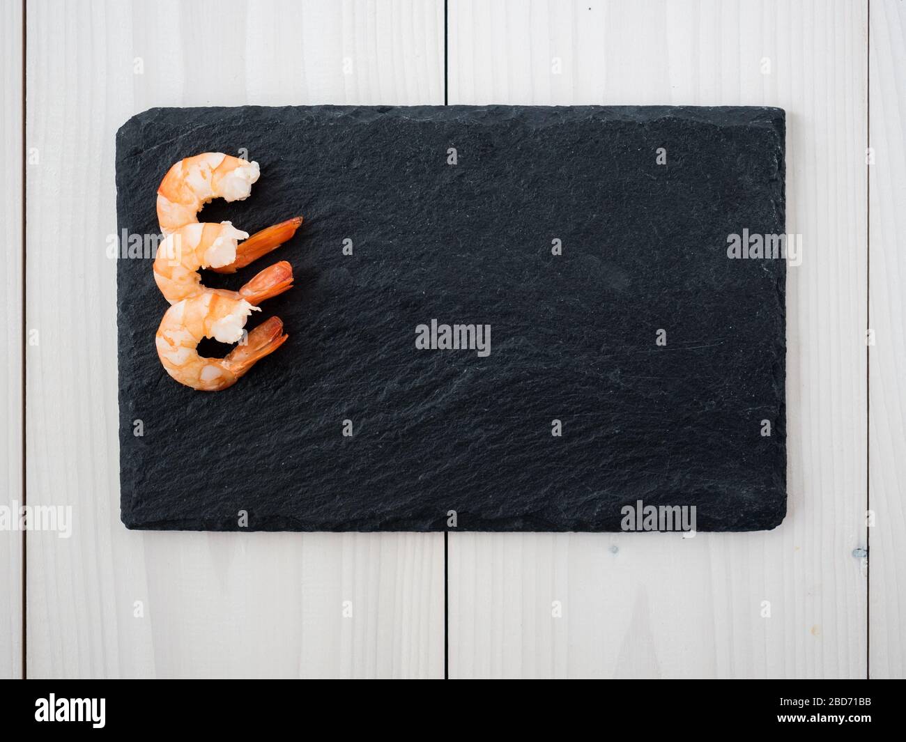 crevettes cuites pelées sur tableau en ardoise. vue de dessus Banque D'Images