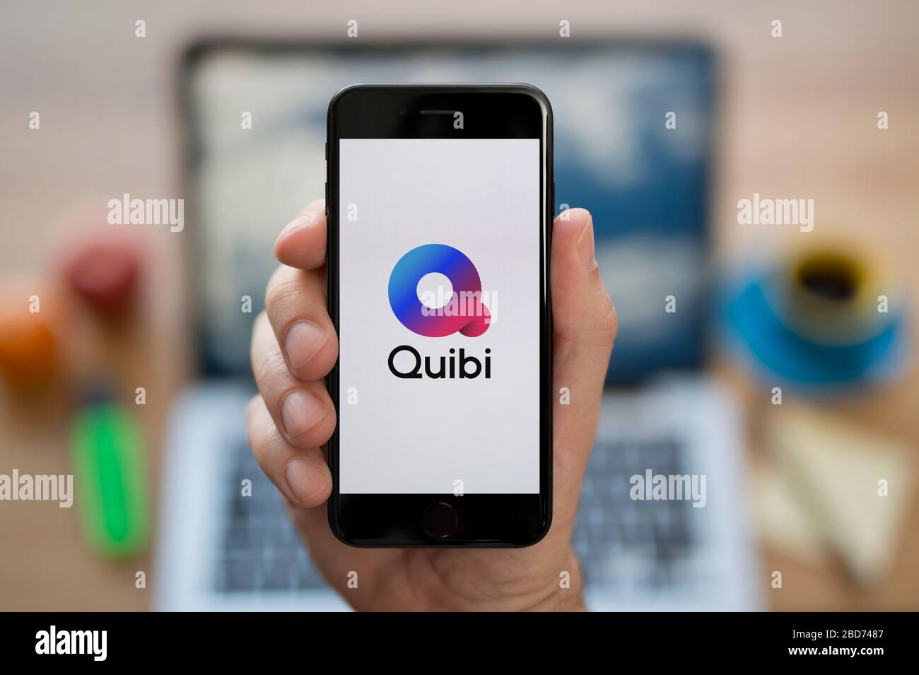 Un homme regarde son iPhone qui affiche le logo Quibi (usage éditorial uniquement). Banque D'Images Un homme regarde son iPhone qui affiche le logo Quibi (usage éditorial uniquement). Banque D'Images