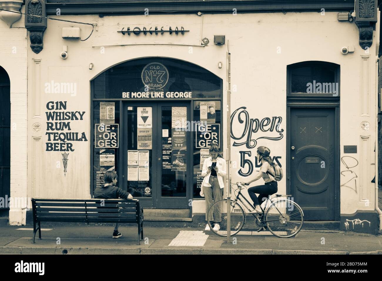 Melbourne Australie - 13 mars 2020 ; Split tonifiez les personnes d'image de style ancien, yougn femme sur mobile, homme assis à l'extérieur et passant le cycliste dehors Banque D'Images