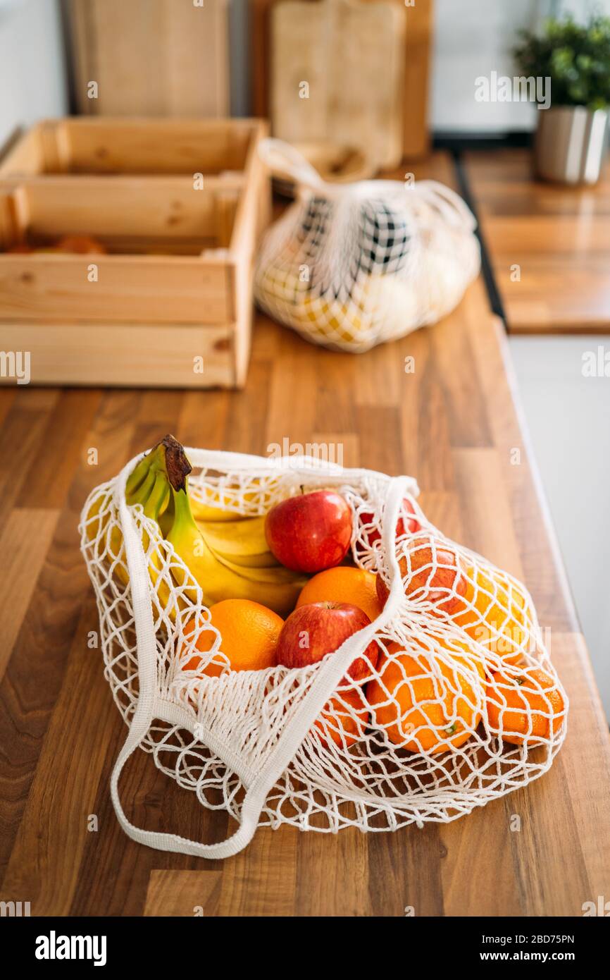 Quelques fruits et légumes dans un sac en maille de coton biologique réutilisable sur fond en bois. Zéro déchet, concept sans plastique. Mode de vie durable. Banque D'Images
