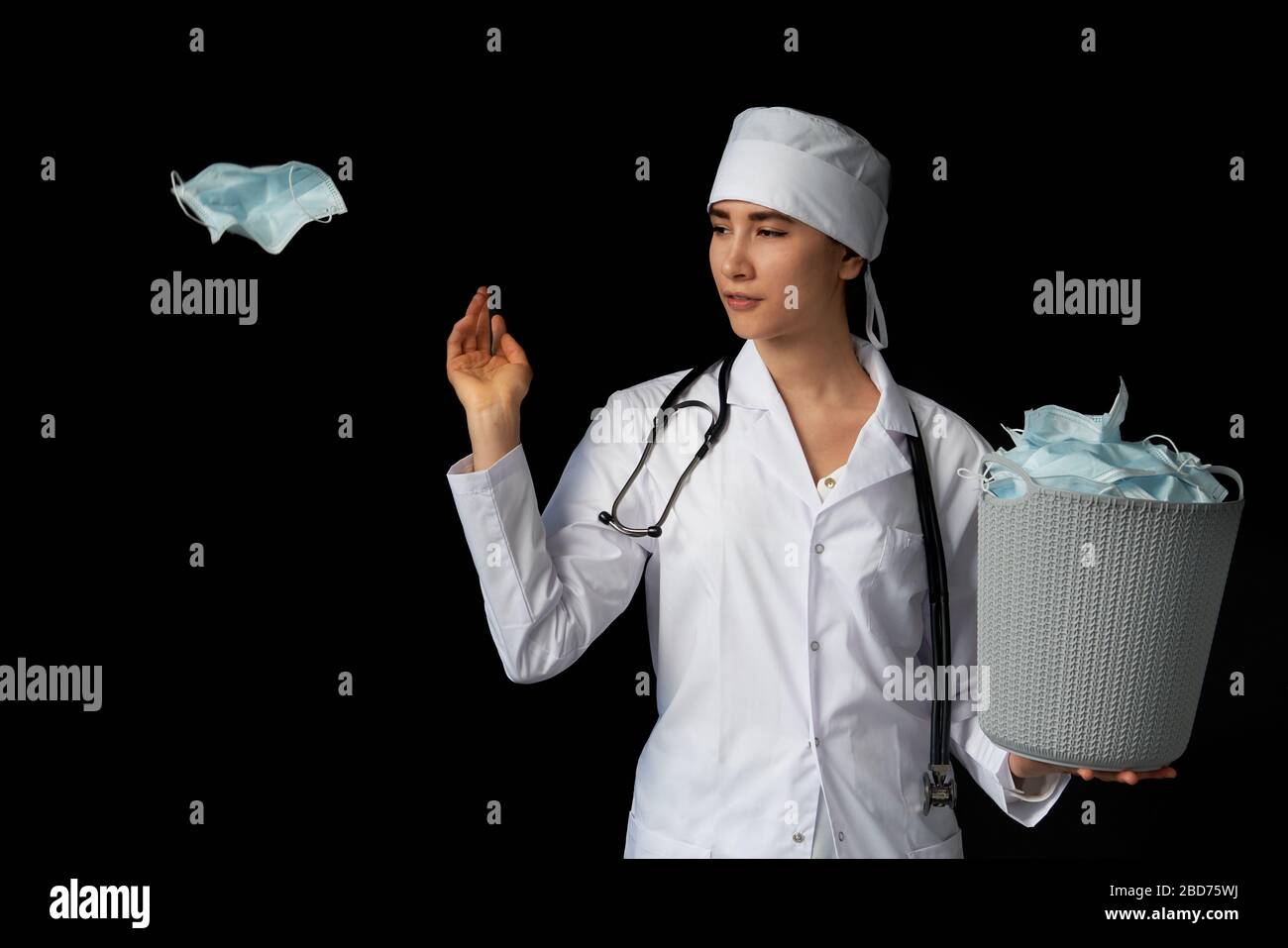 Le médecin tient un seau rempli de masques faciaux usagés, les jetant comme symbole de fin d'épidémie Banque D'Images