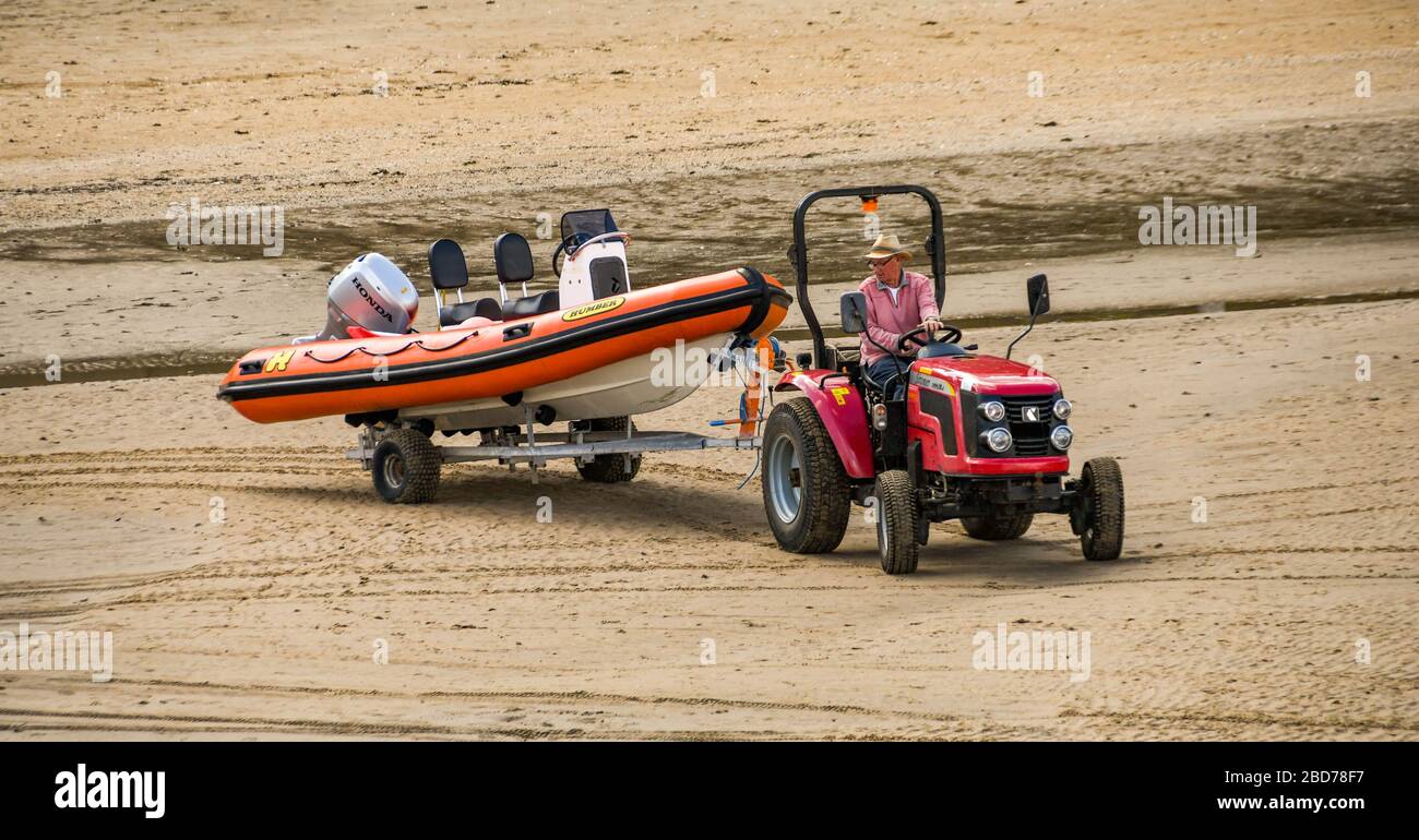 TENBY, PEMBROKESHIRE, PAYS DE GALLES - AOÛT 2018 : tracteur remorqueur d'une remorque avec un bateau à vitesse gonflable dans le port de Tenby, dans l'ouest du pays de Galles à marée basse Banque D'Images