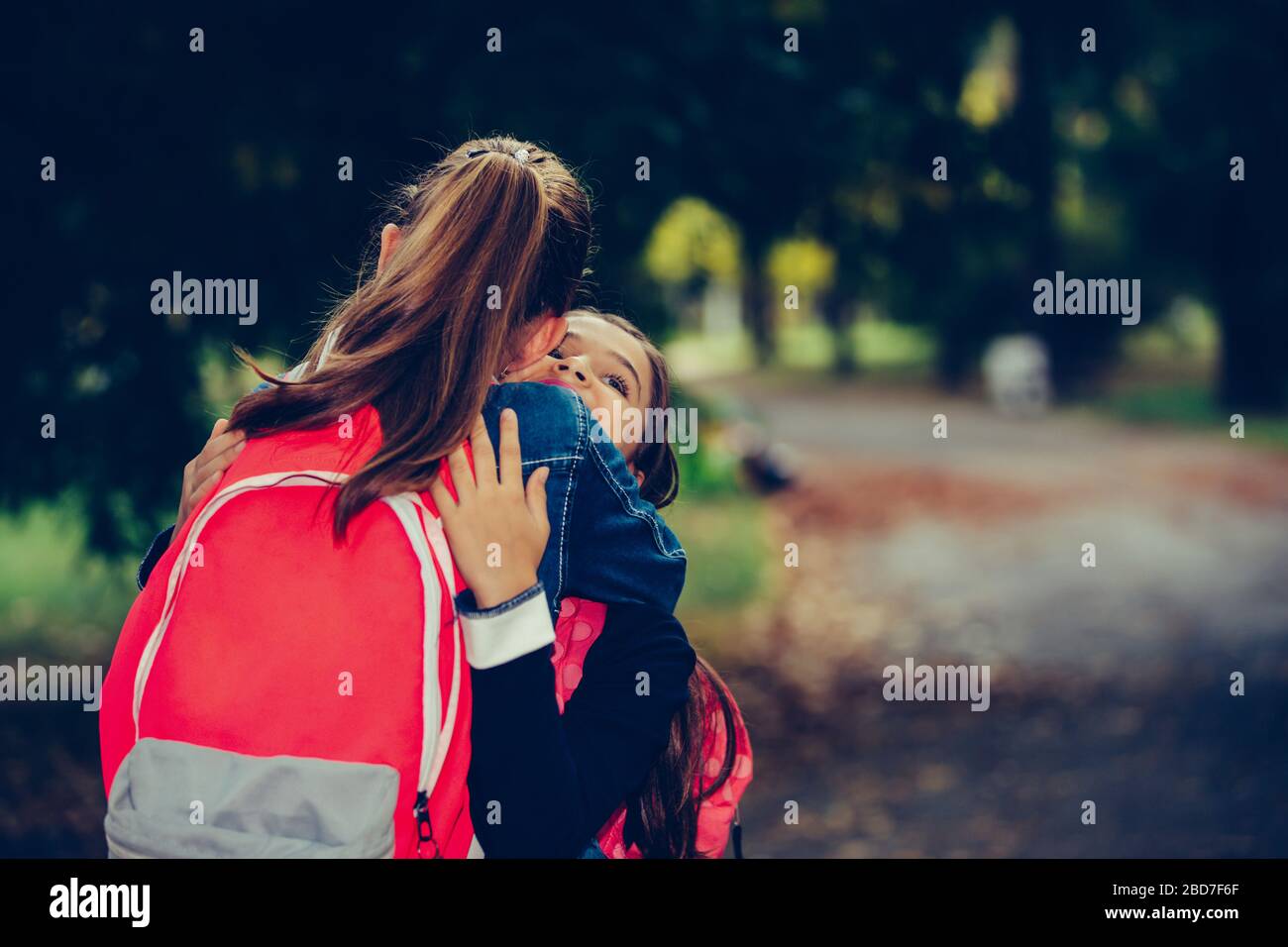 Deux amis de l'école embrassant, rencontrer dans le parc. Marcher les uns dans les autres avec des bras ouverts et sourire. Le concept de l'école, de l'étude, de l'éducation, de l'amitié, Banque D'Images
