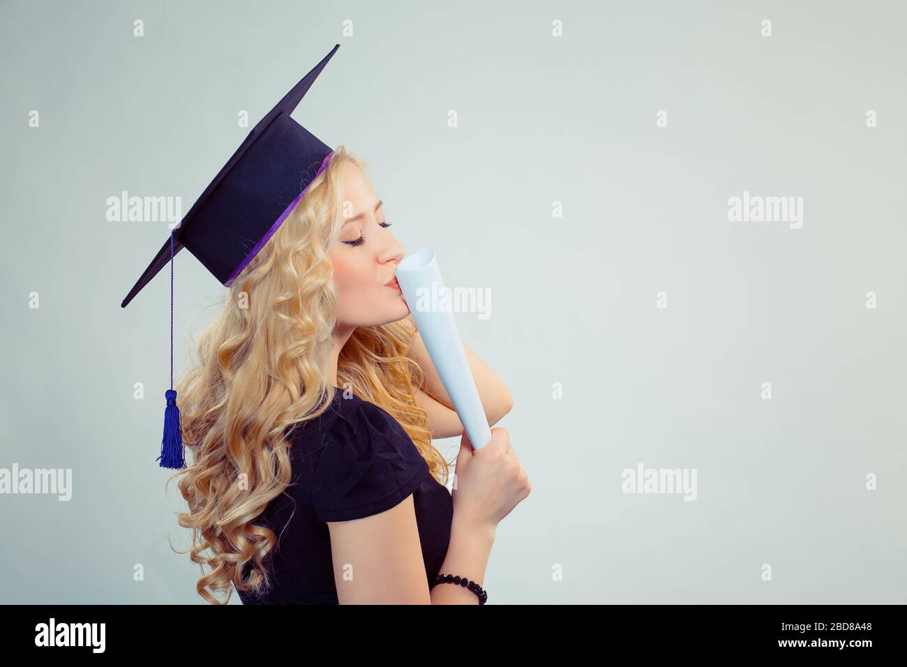 Portrait closeup belle heureuse heureuse latina diplômé, diplômé étudiant jeune fille jeune femme dans la calotte baiser son diplôme défiler plat isolé gree Banque D'Images