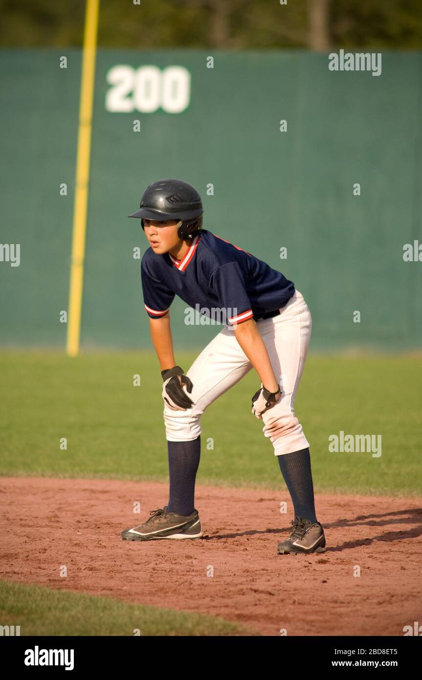 jeune joueur de baseball sur la trajectoire de base avec ses mains sur ses genoux Banque D'Images